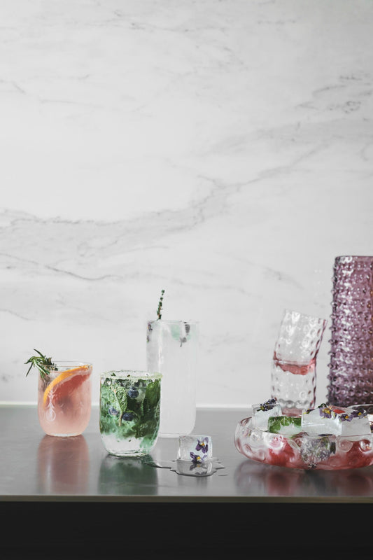 Kodanska Danish Summer Glas auf Marmor, kühle Sommerdrinks mit Blüteneis und Kräutern
