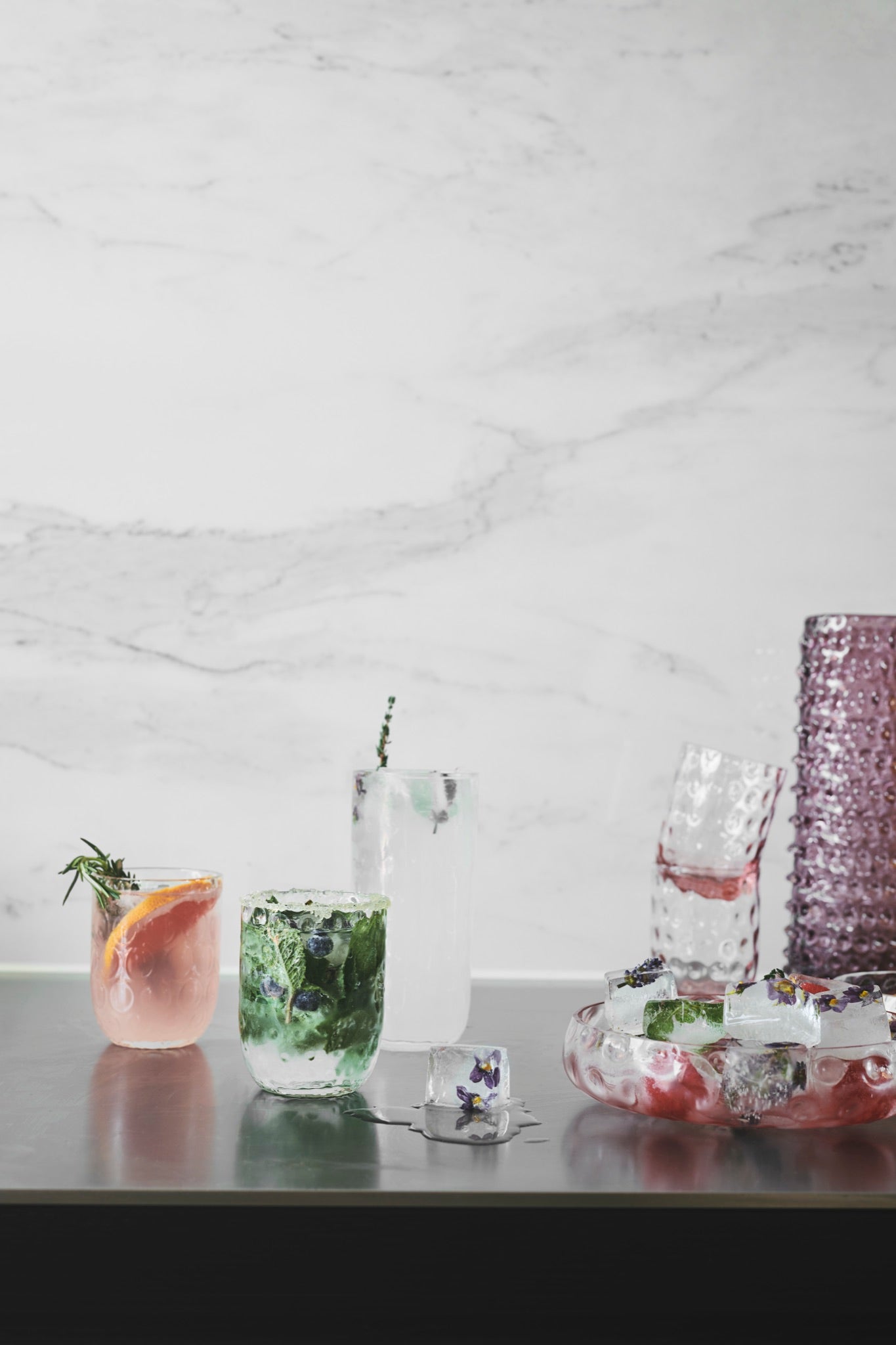 Skandinavisch gedeckter Tisch mit Kodanska Danish Summer Gläsern und Karaffe vor Marmorwand