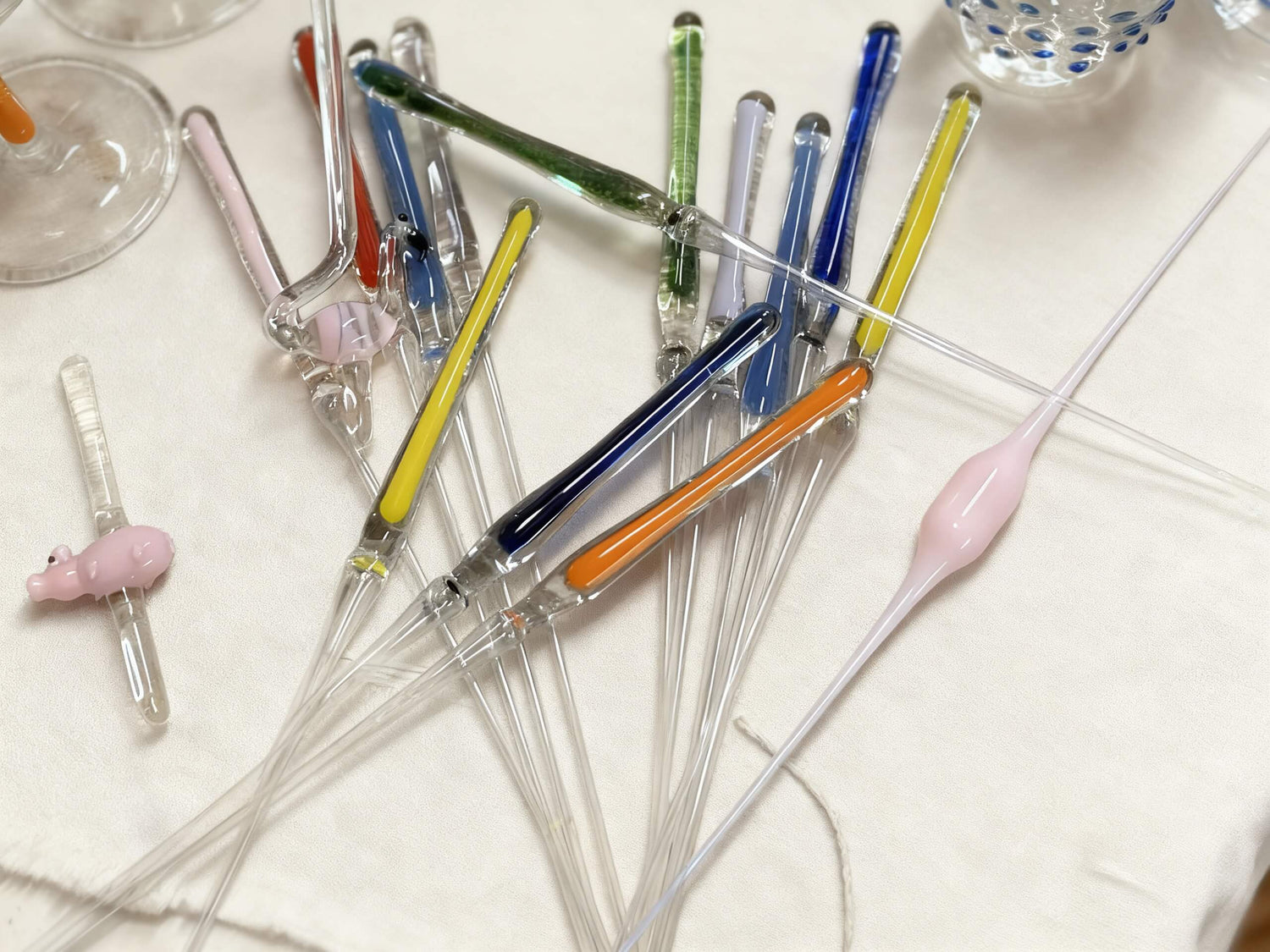 Farbige Glasstiele liegen verteilt auf einem Tisch
