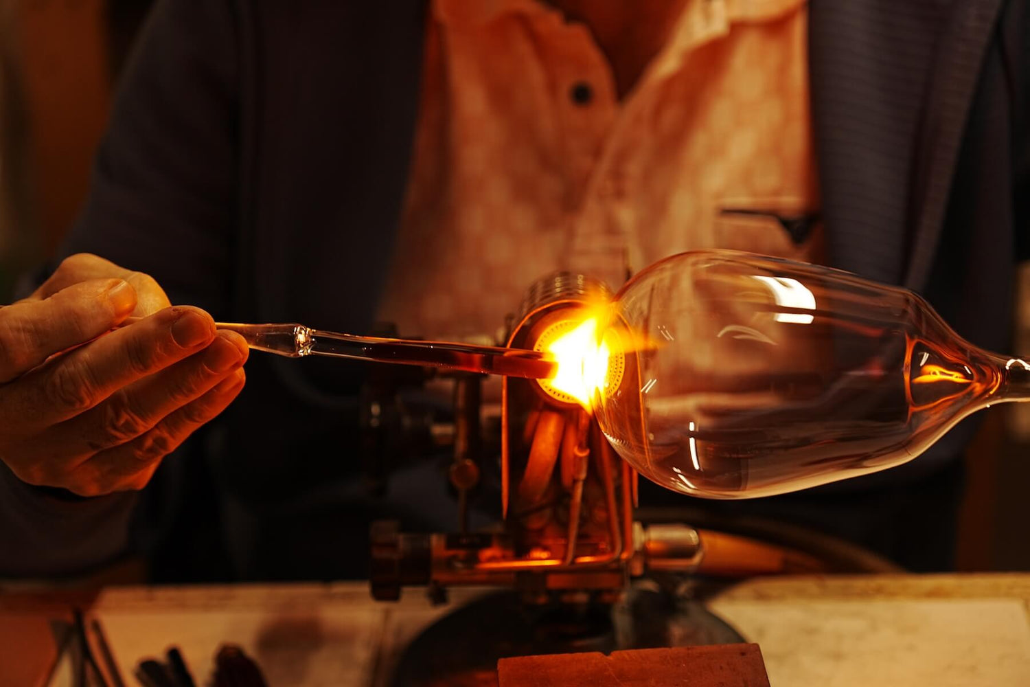 Glasblaeser am Brenner beim Verschmelzen des Stiels mit dem Kelch eines Rotweinglases