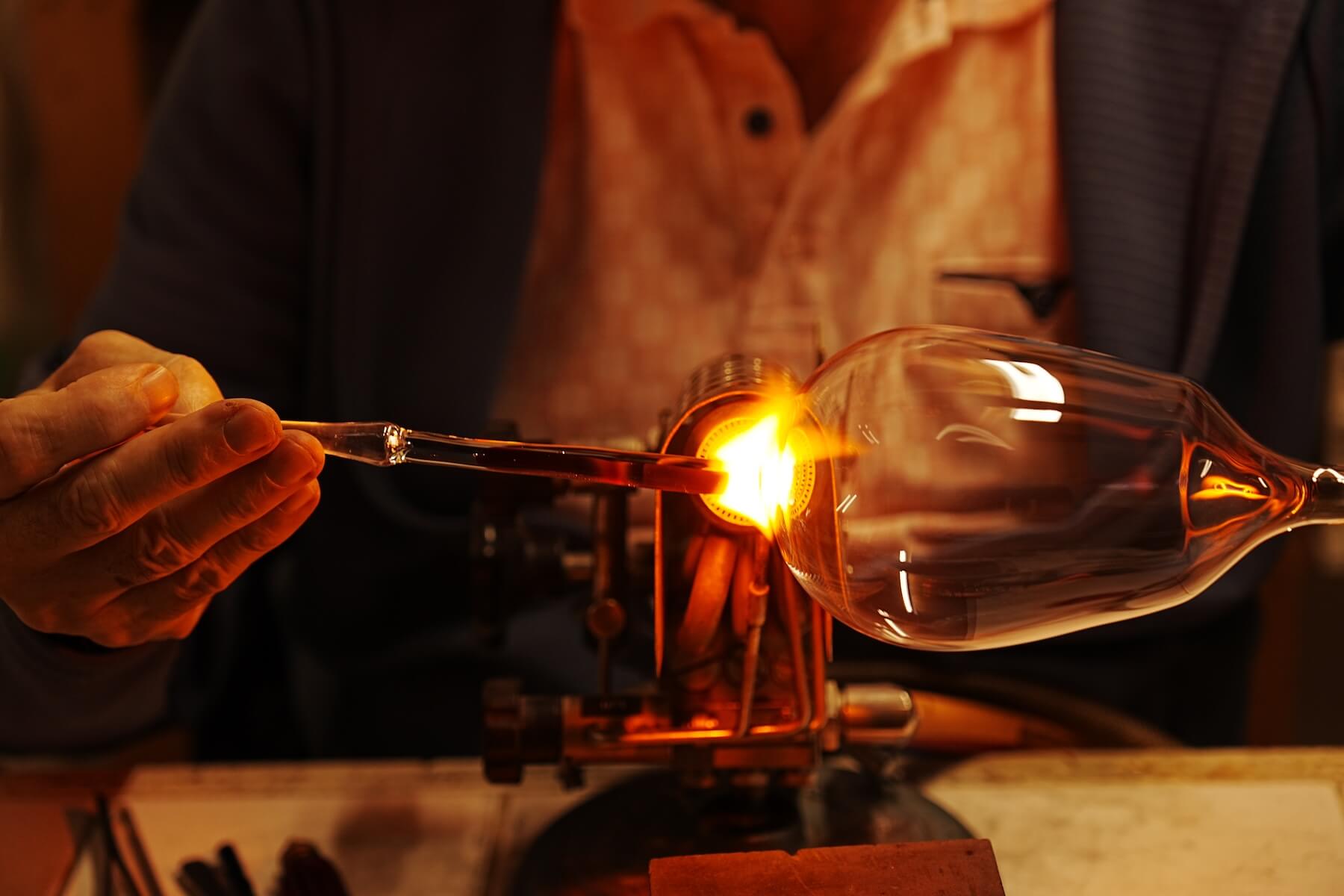 Glasblaeser am Brenner beim Verschmelzen des Stiels mit dem Kelch eines Rotweinglases